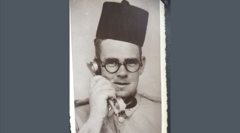 Ronald Skin Moore wearing a fez and talking into a telephone