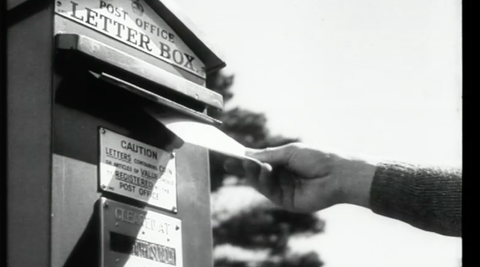 Close up of person putting a letter into a letterbox.