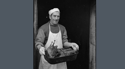 A butcher holding a tray of meat