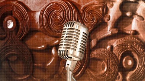 A silver microphone against a background of Māori carvings.