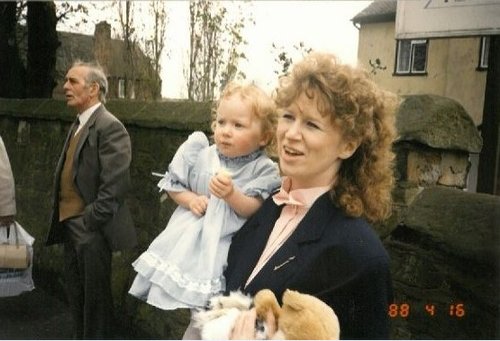 Woman holding a toddler in the eighties.