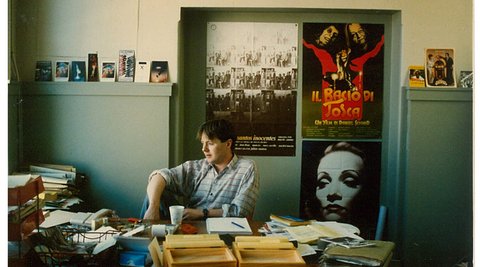 A young Bill Gosden sits behind a messy desk in the office of the NZIF in the 00s.