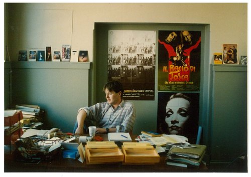 A young Bill Gosden sits behind a messy desk in the office of the NZIF in the 00s.