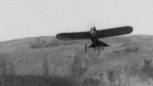 Early airplane taking off in field.