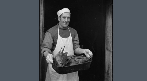 Man holding Christmas turkey in pan.