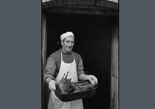 Man holding Christmas turkey in pan.