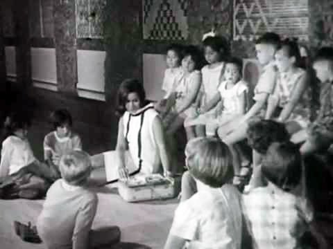 Still from the film 'Don't Let It Get You', with Kiri Te Kanawa demonstrating to children on a marae how her tape recorder assists her training.