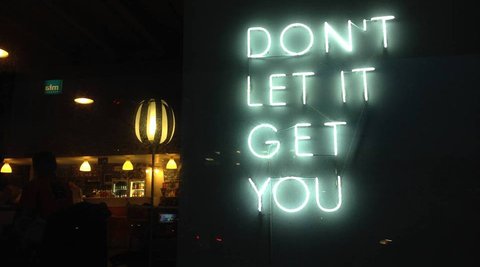 Neon sign that says 'DONT LET IT GET YOU'.