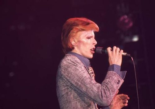 Singer David Bowie is onstage singing into a microphone.