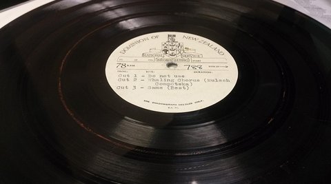 A record on a record player. The label reads 'Dominion of New Zealand, National Broadcasting Service'