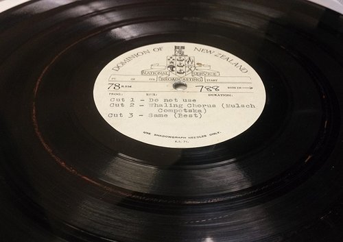 A record on a record player. The label reads 'Dominion of New Zealand, National Broadcasting Service'.