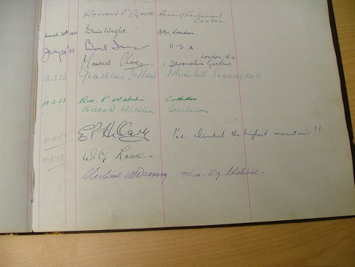 An old leather bound visitor book opened to show Edmund Hillary's signature on a page