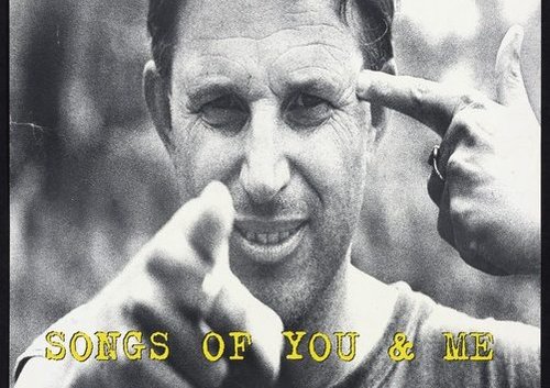 Musician Chris Knox is pointing one finger at the camera and another at his head. Yellow text reads 'Songs of You and Me Available now on Flying Nun Records in a Really Really Yellow Plastic Case'