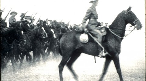 A soldier on horseback leads a number of other soldiers on horseback.