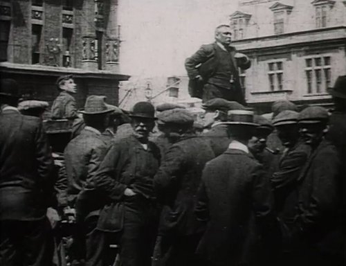 A crowd of men are standing around another man who is on a raised platform.