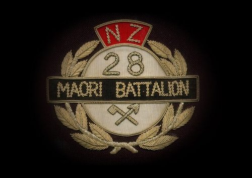 A Māori Battalion embroidered badge with a wreath and an arrow and axe crossed over.