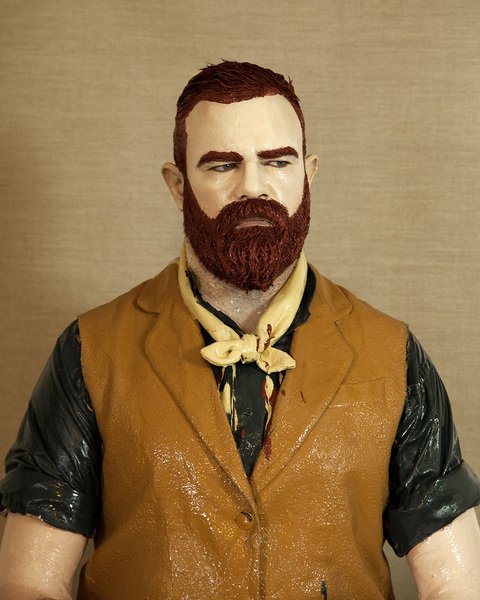 A ceramic figure of a man with a red beard and red hair wearing a vest and a kerchief