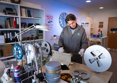 A man in a lab coat winding film in a preservation suite