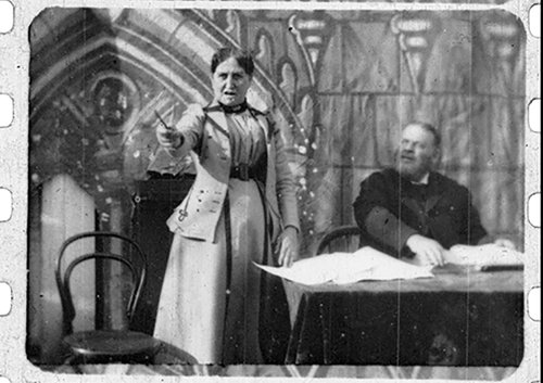 Woman standing and man sitting at desk.