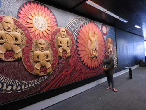 A young woman poses in front of a Māori mural