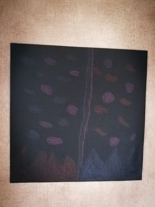 A child's painting is on a wall. It depicts spots and triangles and a line down the middle.