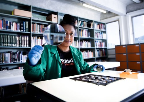 Woman holding magnifying glass in archive facility.