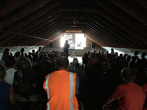 A large crowd in front of the screen set up in the woolshed.
