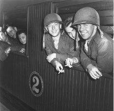 A group of marines are leaning out of a train window and smoking cigarettes