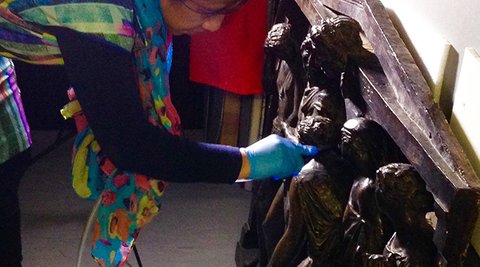 Woman cleaning a plaque with a HEPA filter vacuum.