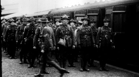 A large group of soldiers are standing on a platform in front of a train