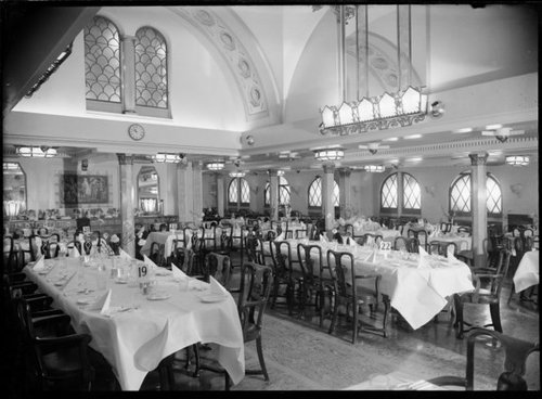 The cafe on board the Wanganella. An ornate room with long tables with white tablecloths.