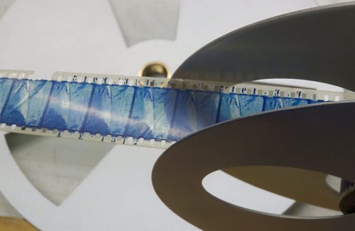 A reel of blue film is being wound through.