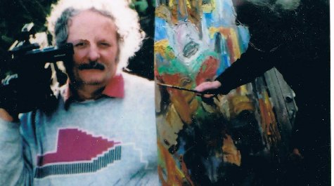 Two images of Peter Coates. In the first he is carrying a film camera on his shoulder, in the second, he is painting a brightly coloured painting.