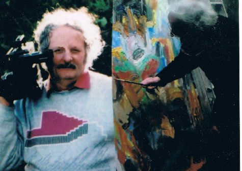 Peter Coates holding a video camera (left) and painting a canvas (right).