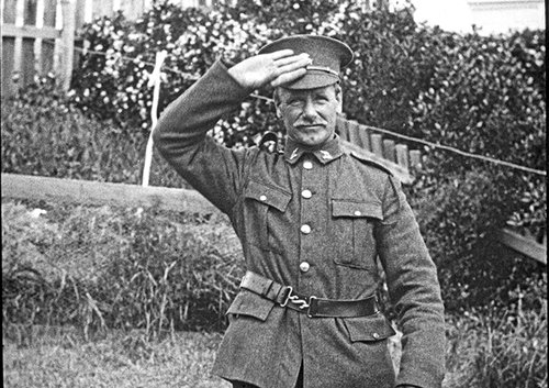 A man in a first World War army uniform salutes the camera.
