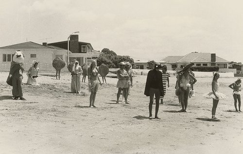A group of actors pose on a beach, wearing assorted sea-themed costumes