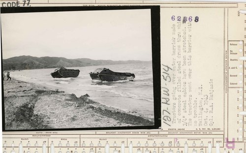 Two amphibian tractors are coming in to land on Petone Beach in 1943. Two men onshore are filming.