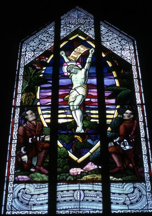 Stain glass window depicting Two Māori soldiers look up at Christ on the cross.
