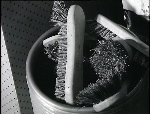 A number of scrubbing brushes are in a bucket.