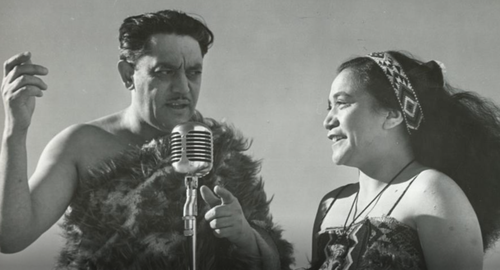 Image of Ōriwa Tahupōtiki Haddon talking into an old radio microphone, stranding with a maori woman.