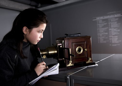 Child looking at projector and taking notes