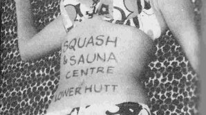 Woman in a bikini with the writing 'Squash & Sauna Centre, Lower Hutt, on her stomach.