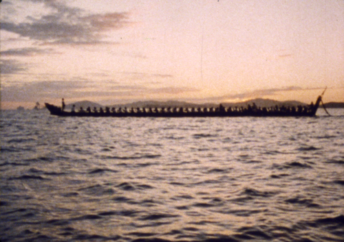 Silhouette of large waka in open water.