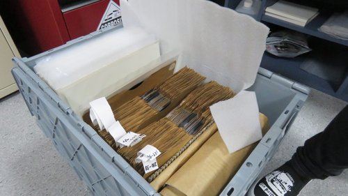 A crate of old records in paper sleeves