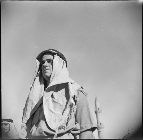 A man in an Arab headdress looks into the distance