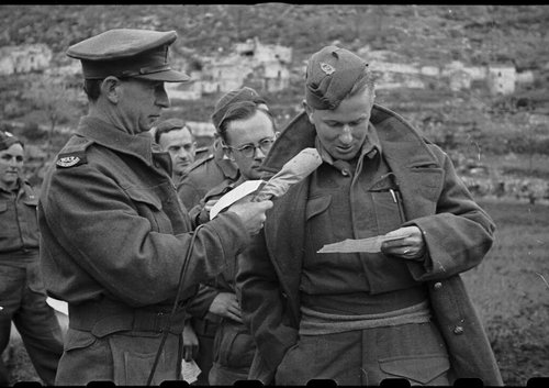 A man holds a microphone for a soldier who reads from a letter