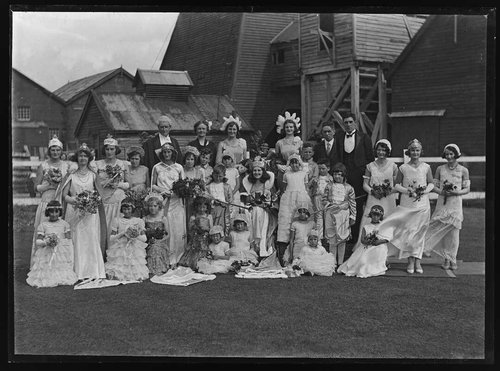 A row of people in fancy dress pose in front of a West Coast mine, as part of their small town's Queen Carnival.