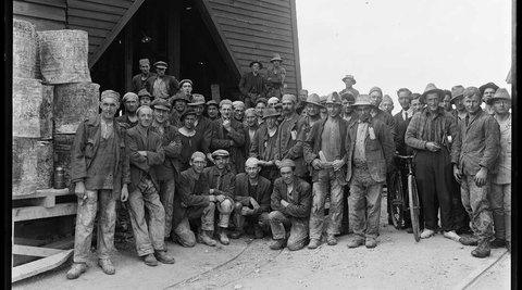A group of workers pose outside a rough looking mine entrance, some time in the 1920s or 1930s..