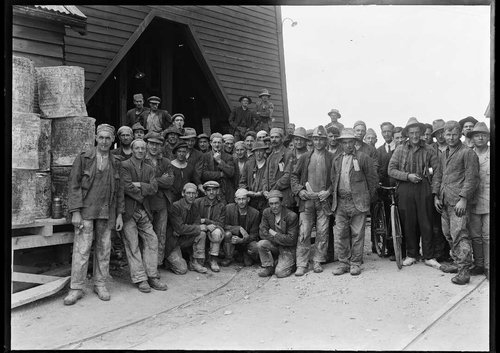 A group of workers pose outside a rough looking mine entrance, some time in the 1920s or 1930s..
