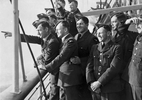 A group of soldiers pointing and looking at land from a ship